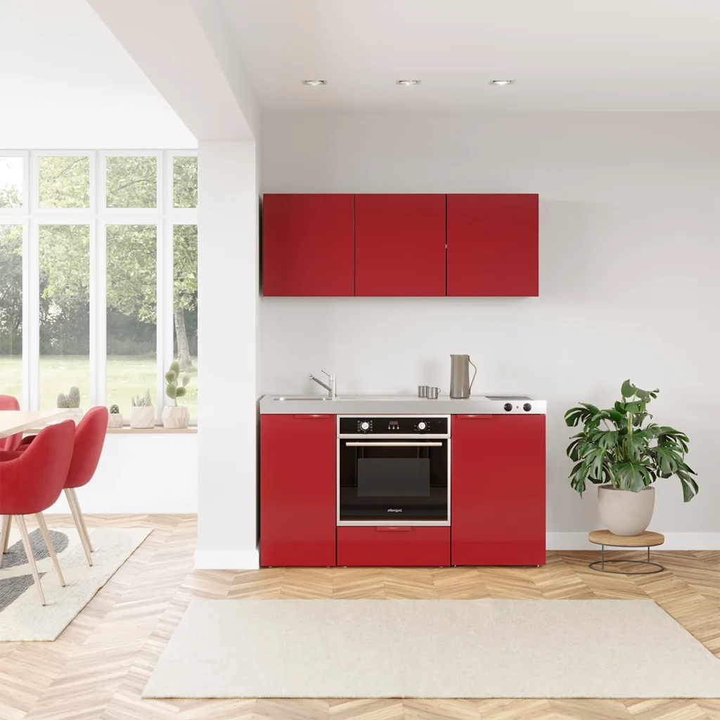 3D Rendering einer roten Miniküche mit Backofen in einer offenen Wohnküche in einer Ferienwohnung umgeben von einem Esstisch mit roten Stühlen, einem Teppich und einer Monstera Pflanze